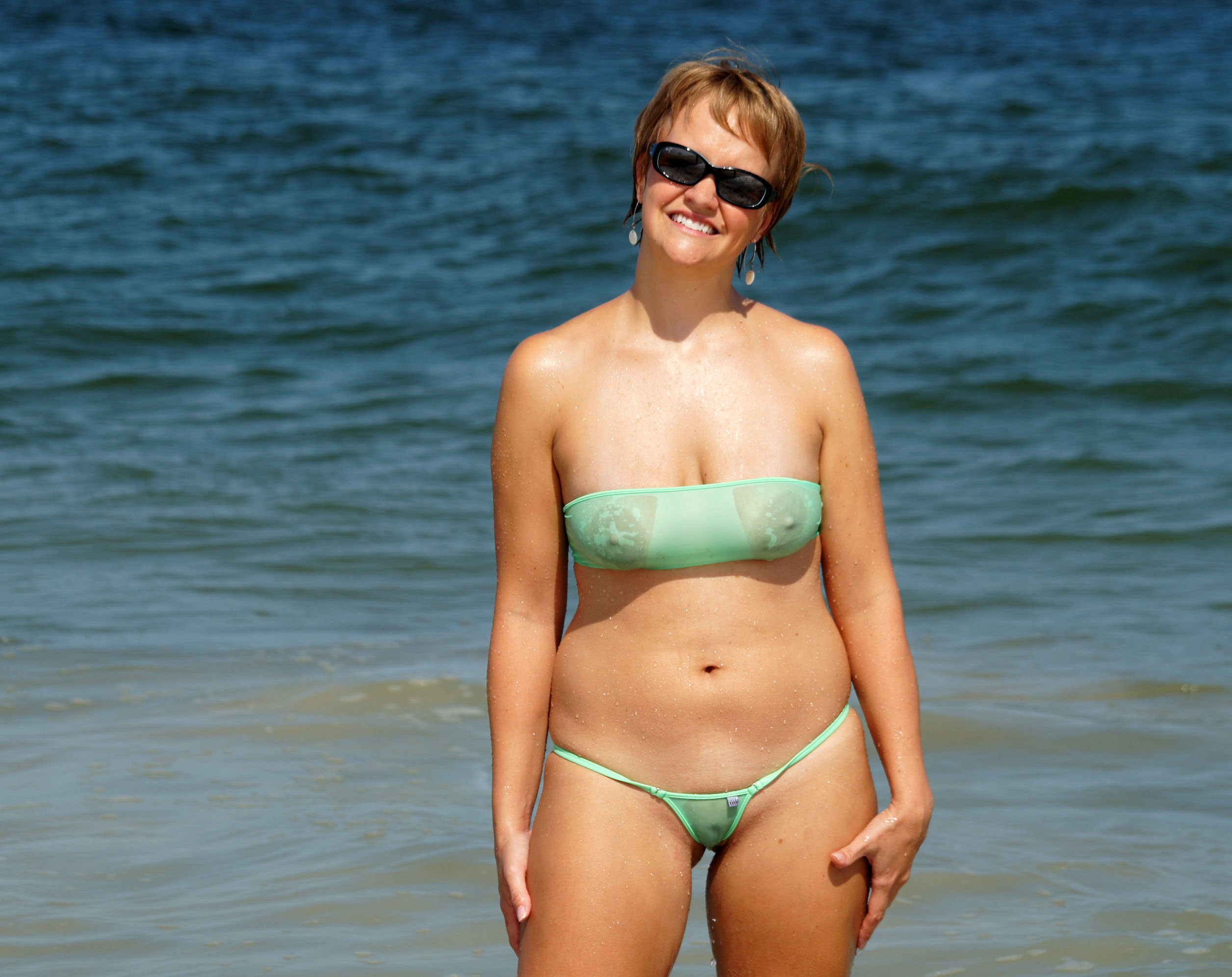 milf smiling on the beach fully exposed in her see through bikini
